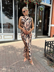 Woman wearing tiger print high neck maxi dress with open back and slit up the side.