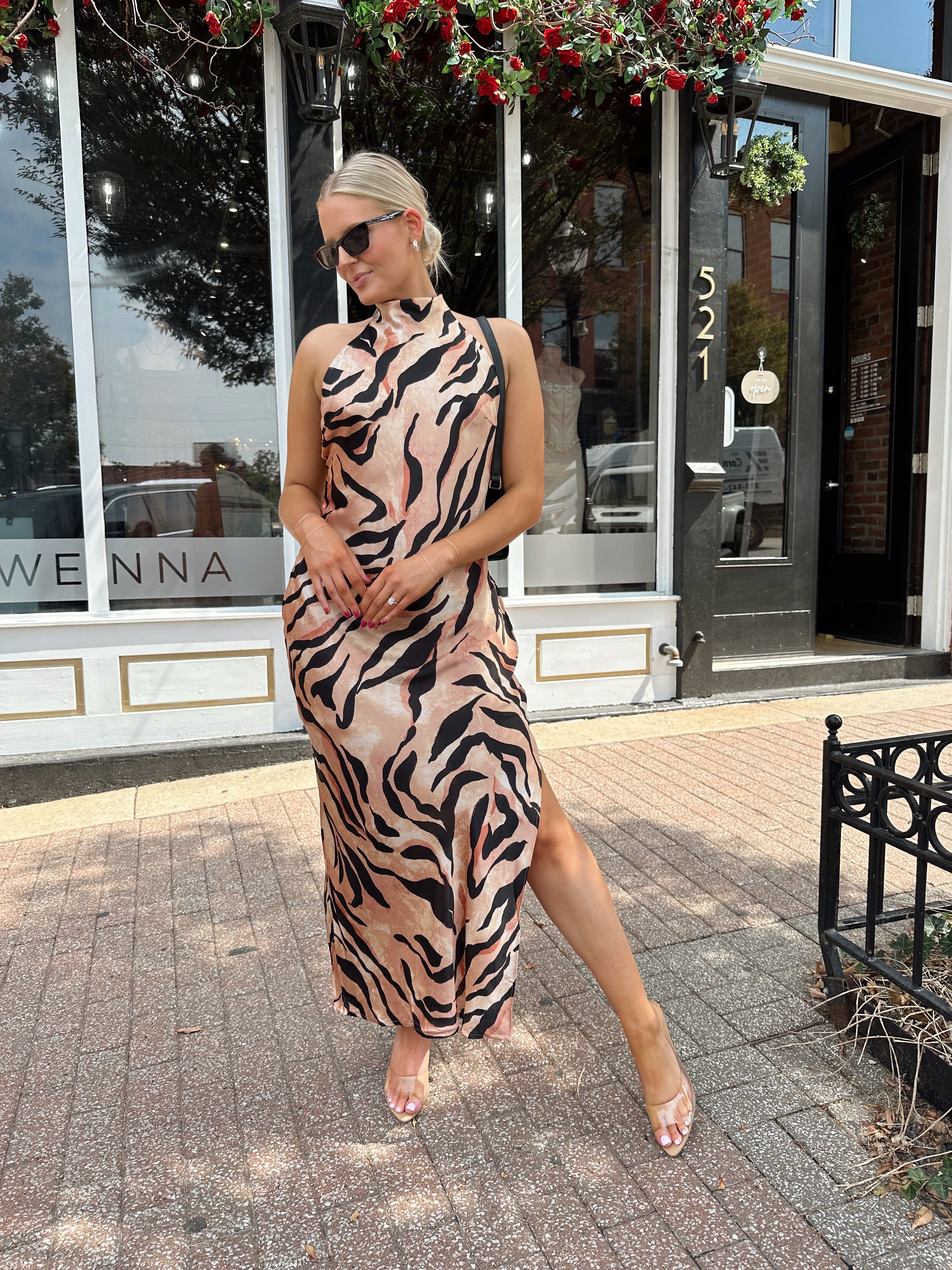 Woman wearing tiger print high neck maxi dress with open back and slit up the side.