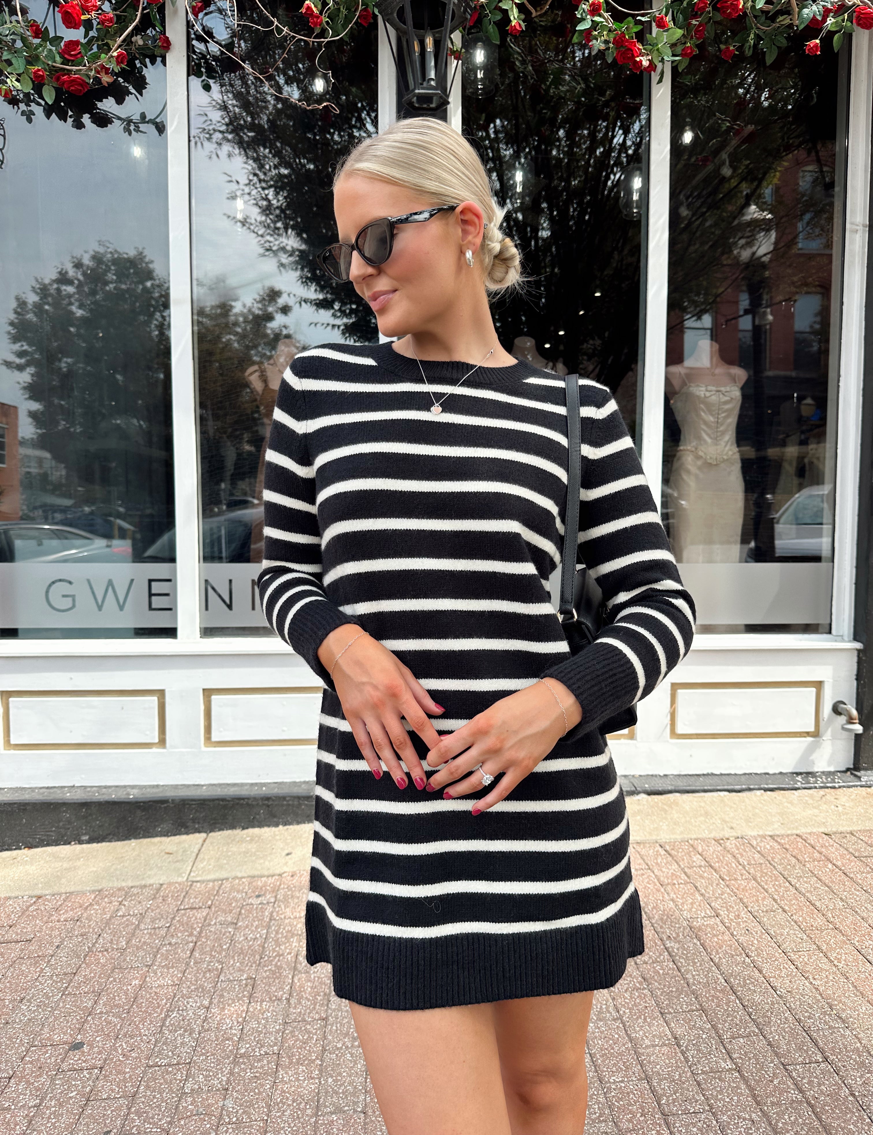 Woman wearing black and white striped long sleeve sweater dress with black chunky heel.