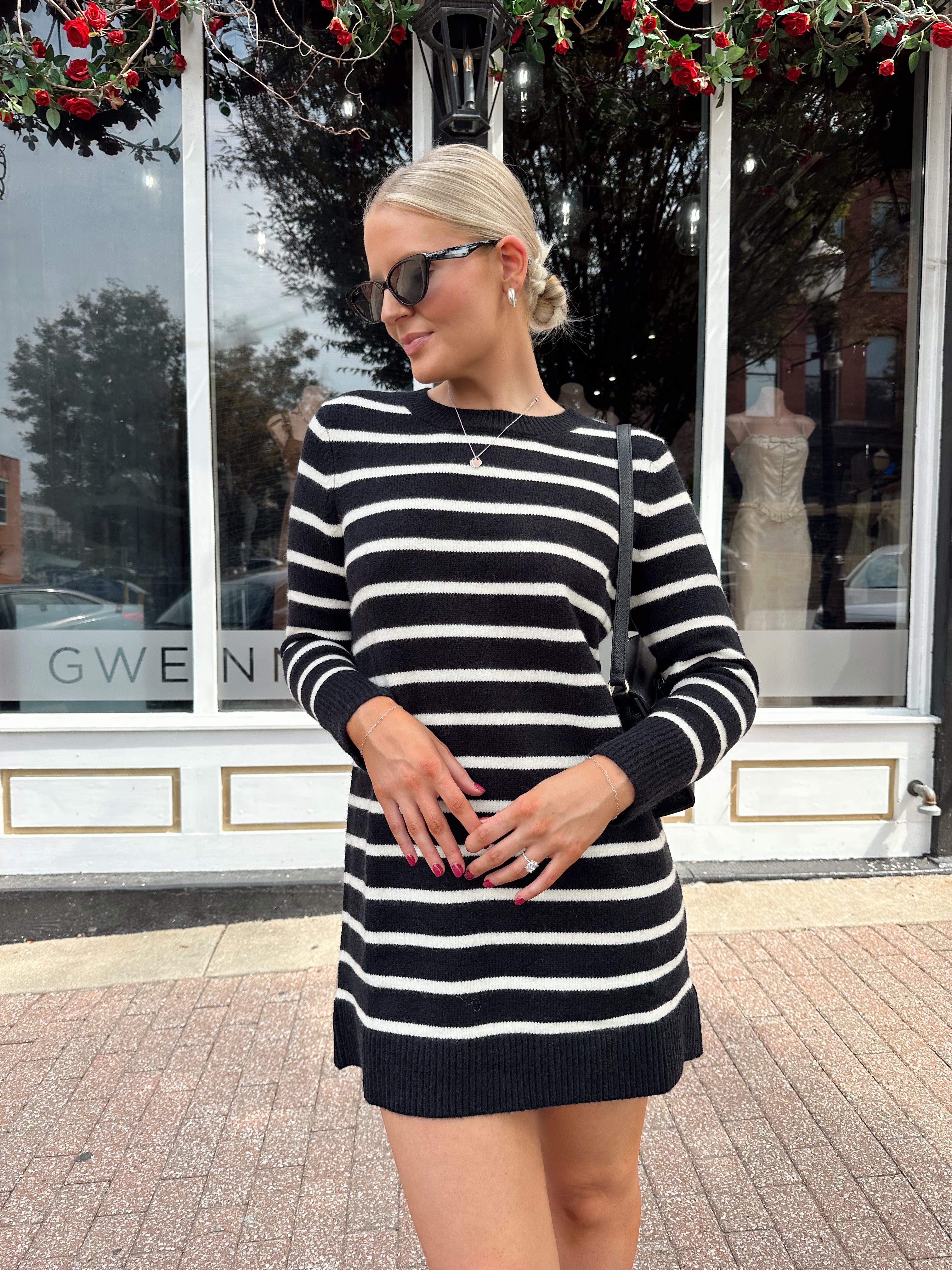 Woman wearing black and white striped long sleeve sweater dress with black chunky heel.