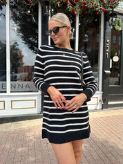 Woman wearing black and white striped long sleeve sweater dress with black chunky heel.
