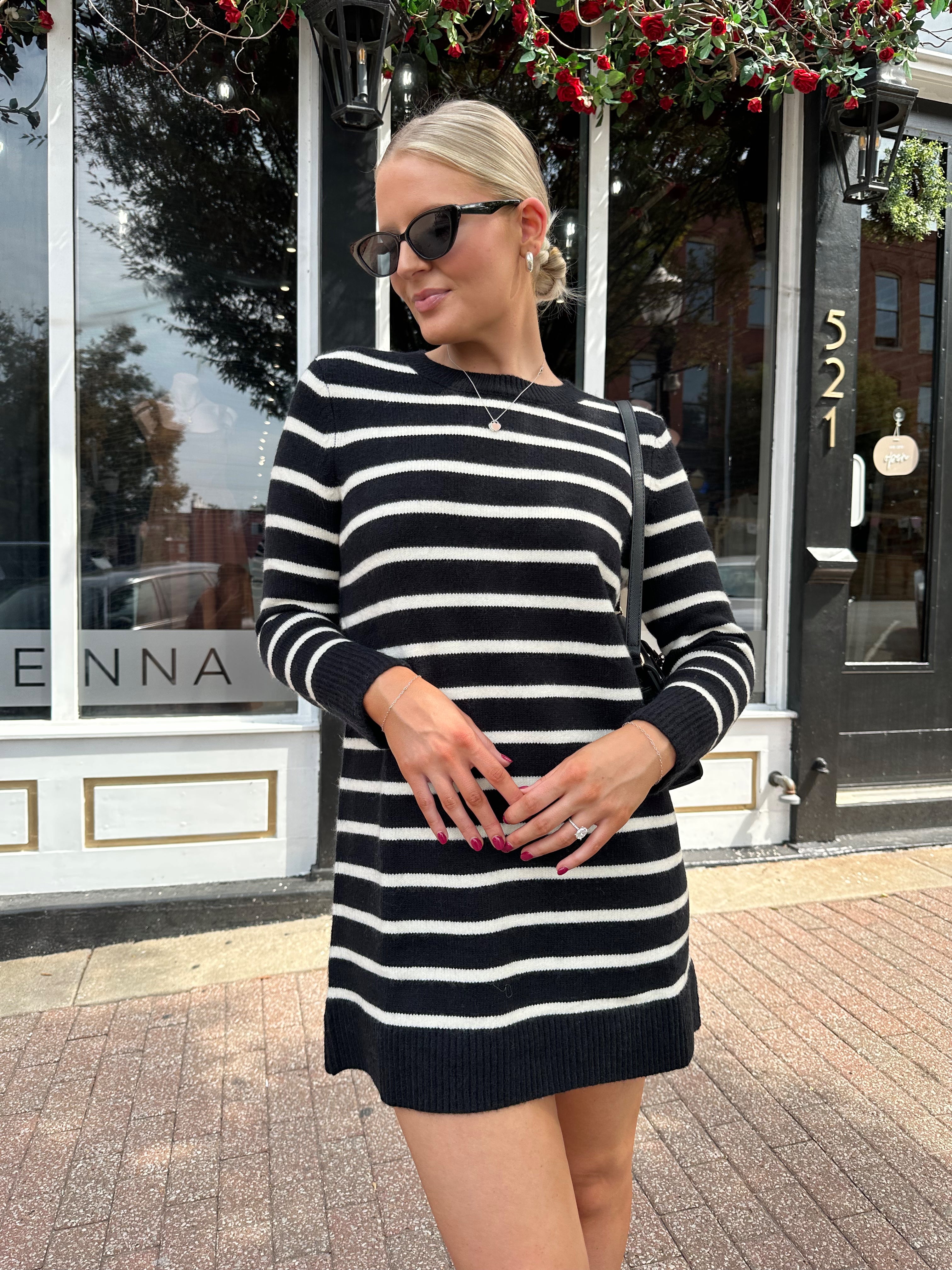 Woman wearing black and white striped long sleeve sweater dress with black chunky heel.