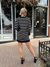 Woman wearing black and white striped long sleeve sweater dress with black chunky heel.