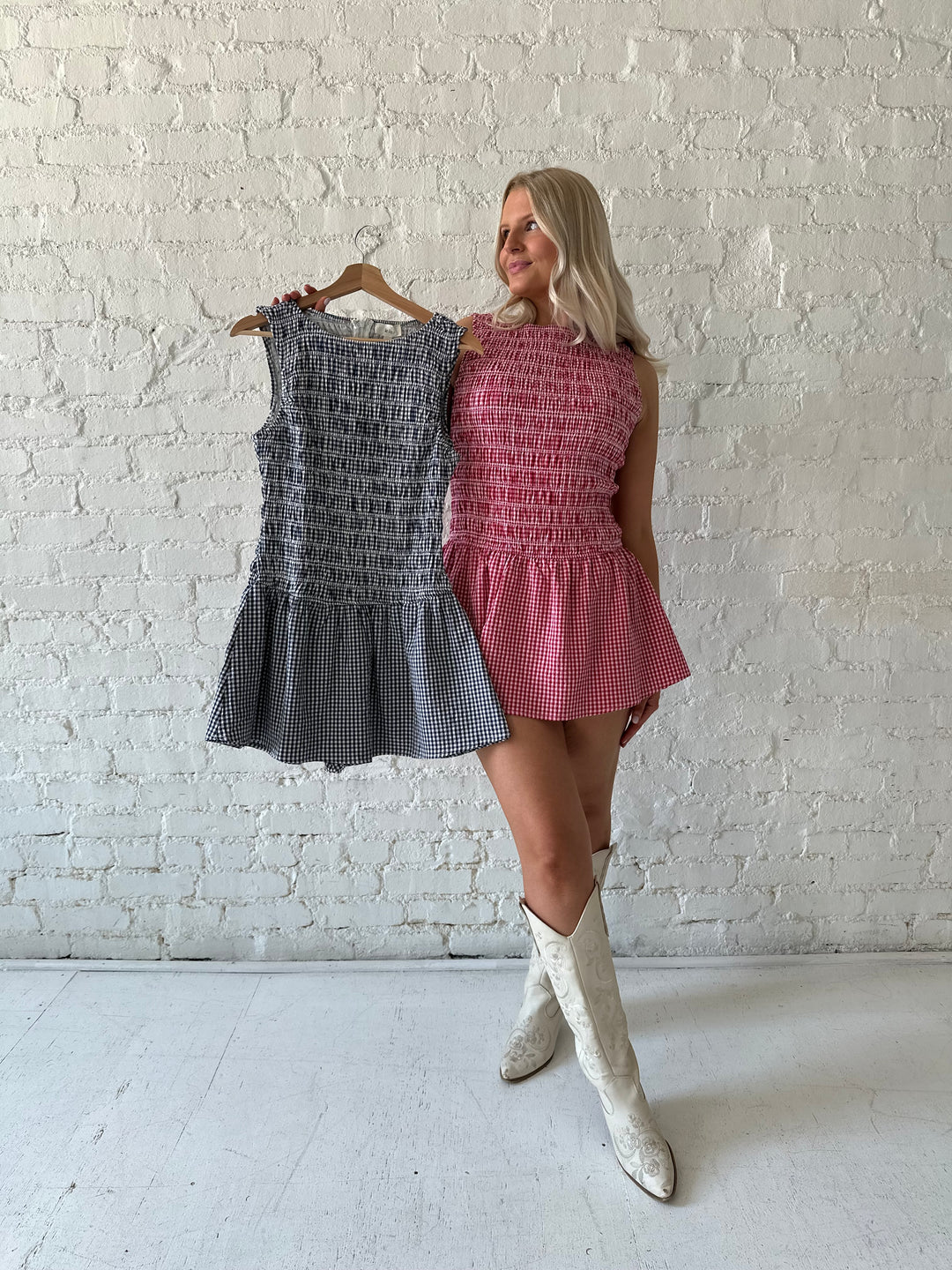 Woman wearing navy gingham smocked mini dress with built in shorts.