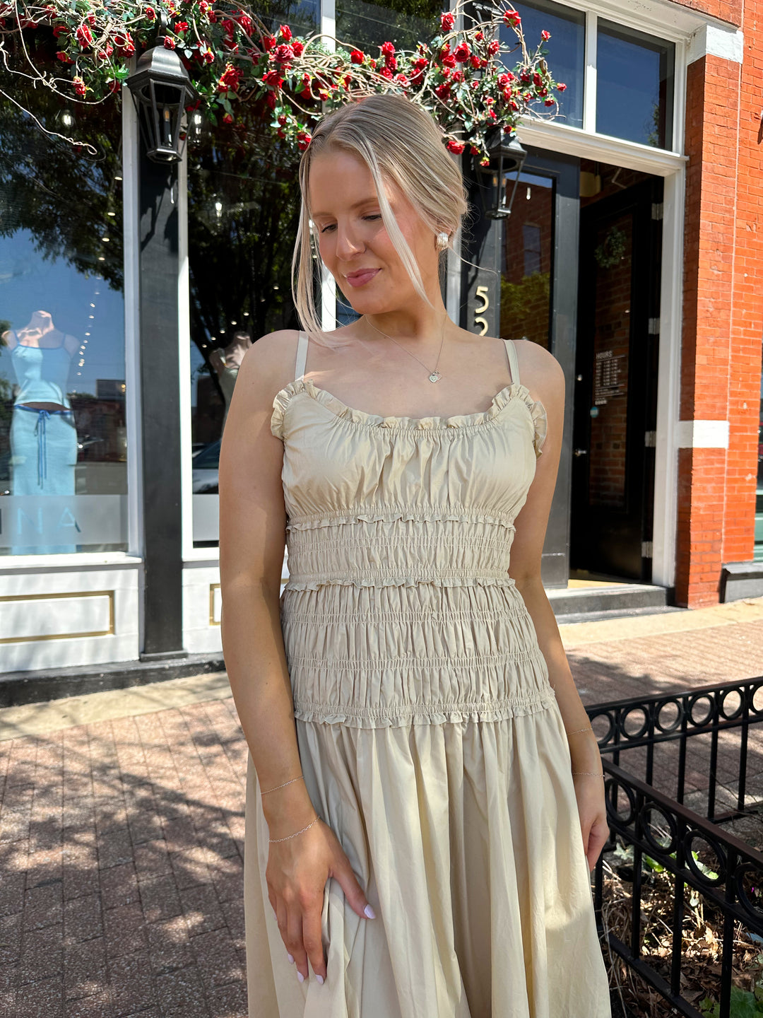 Woman wearing tan maxi dress with smocked bodice, adjustable spaghetti straps, and side slit. 