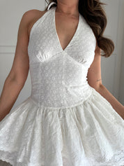 White eyelet mini dress with a self-tie halter neck and a flared skirt.
