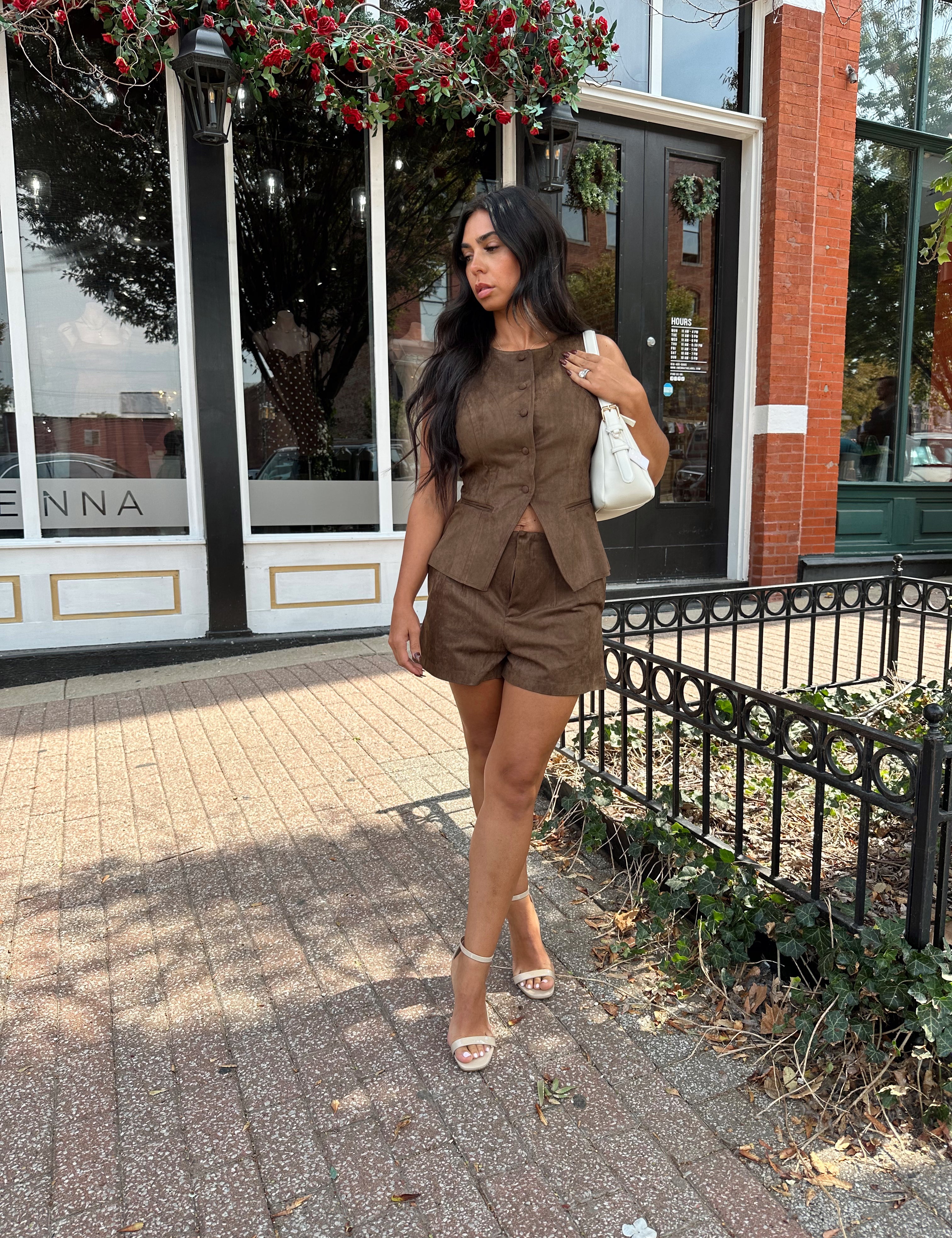Woman wearing espresso brown suede button up vest with matching shorts.