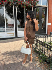 Woman wearing espresso brown suede button up vest with matching shorts.