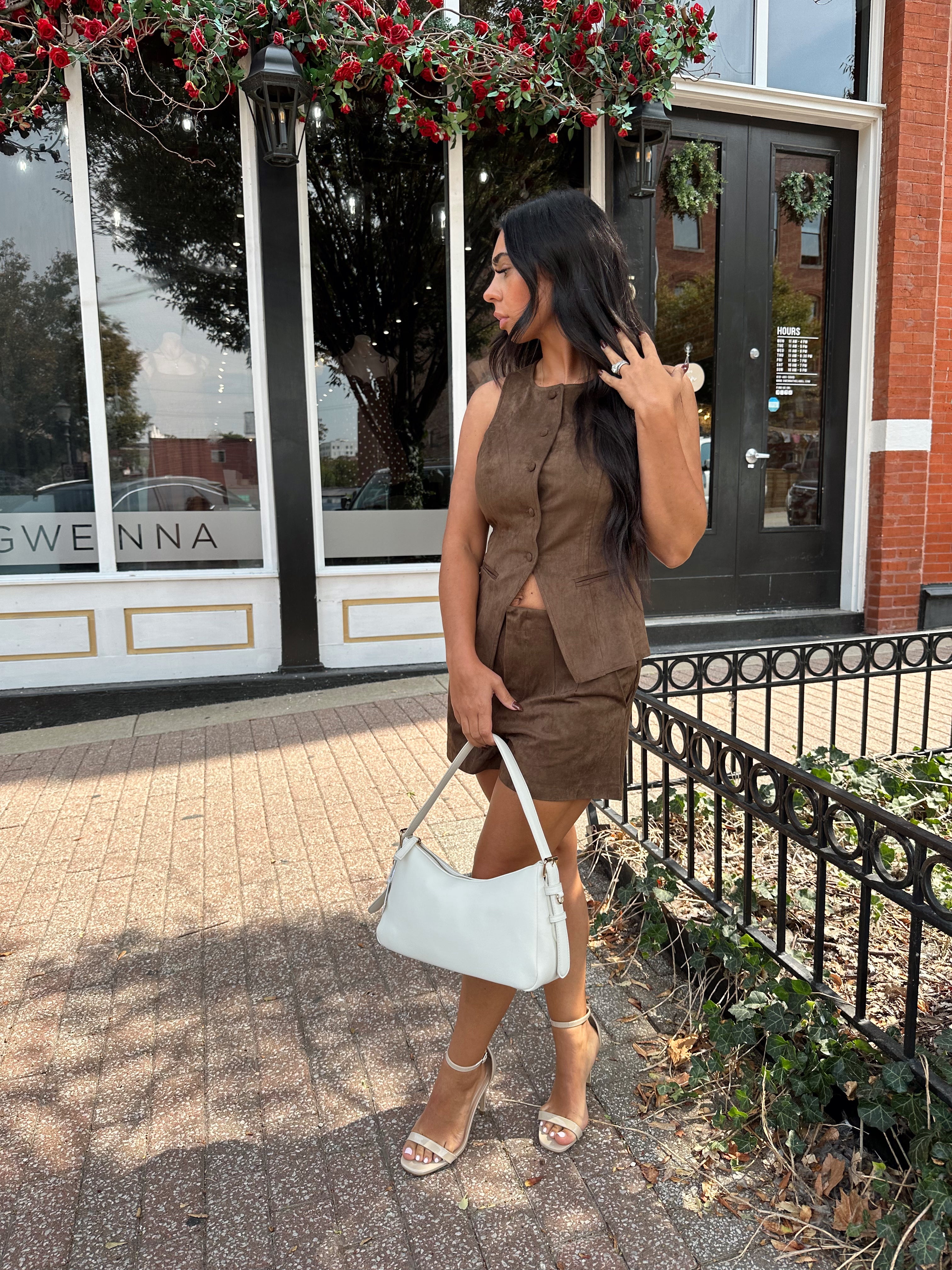 Woman wearing espresso brown suede button up vest with matching shorts.
