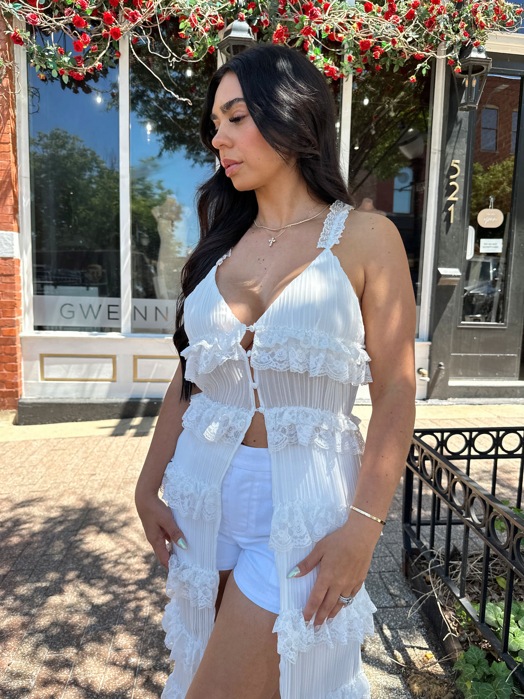 Woman wearing white sheer overlay duster with ruffle tiered detailing, and button closure.