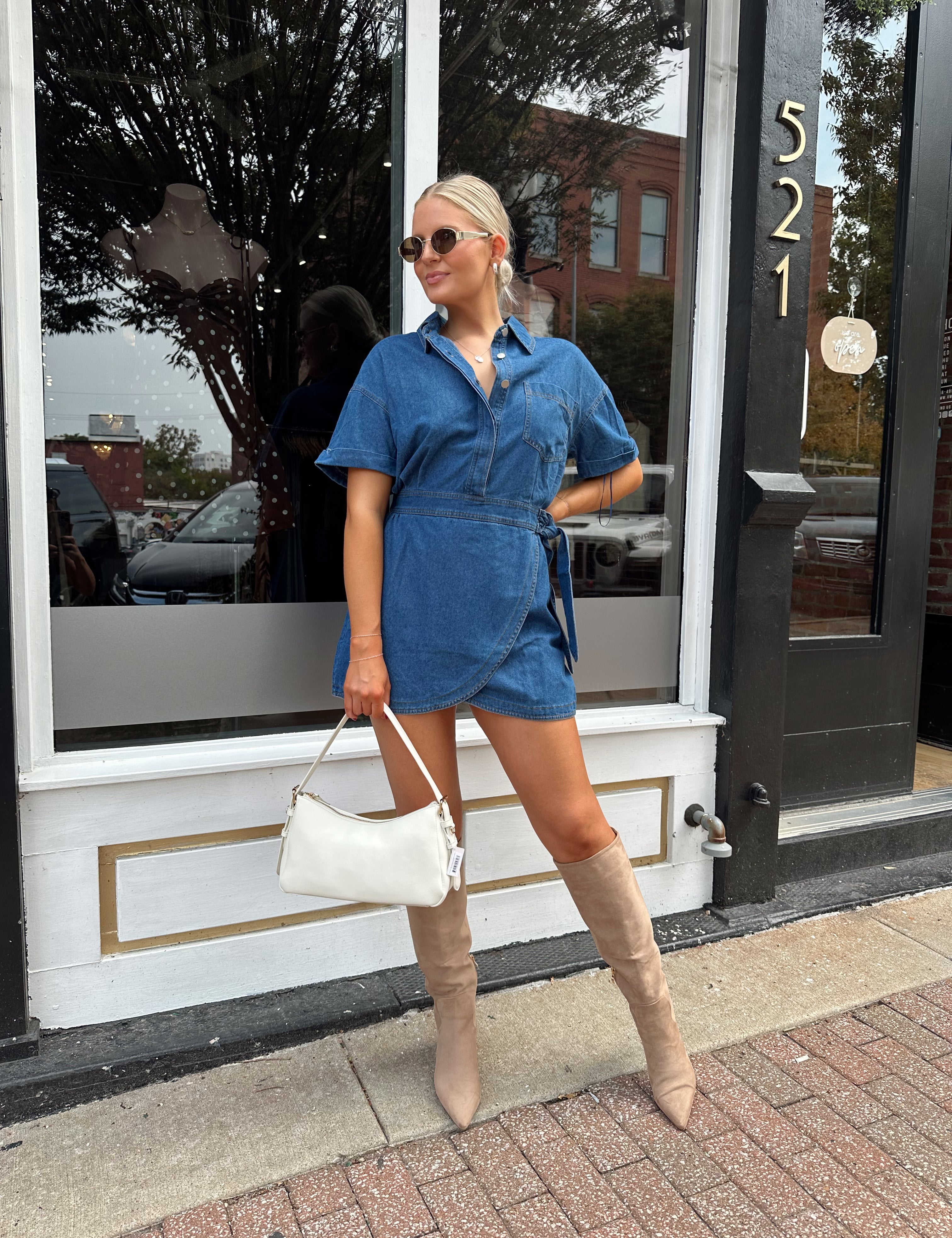 Woman wearing short sleeve dark wash denim dress with wrap skirt detail. 