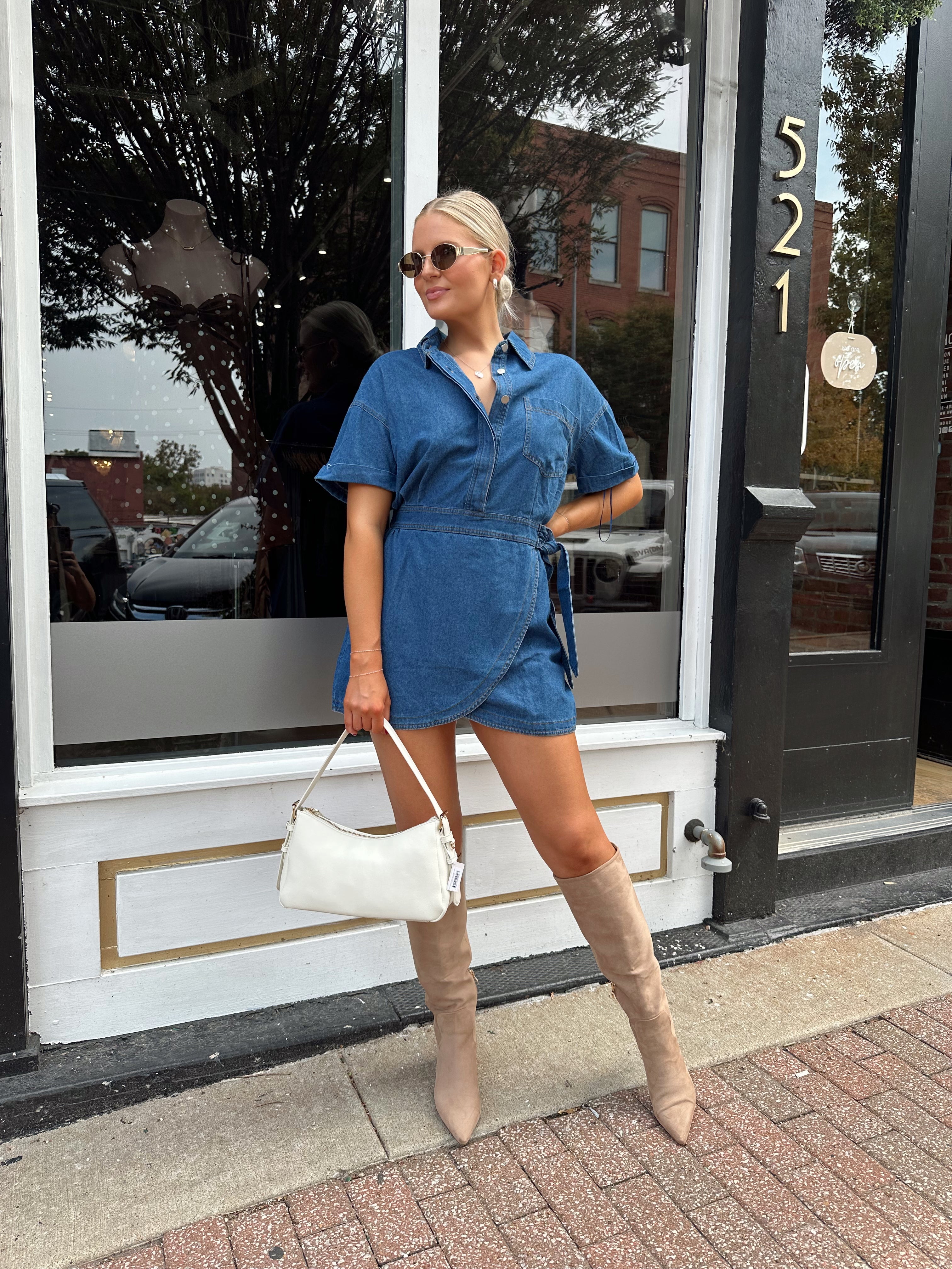 Woman wearing short sleeve dark wash denim dress with wrap skirt detail. 