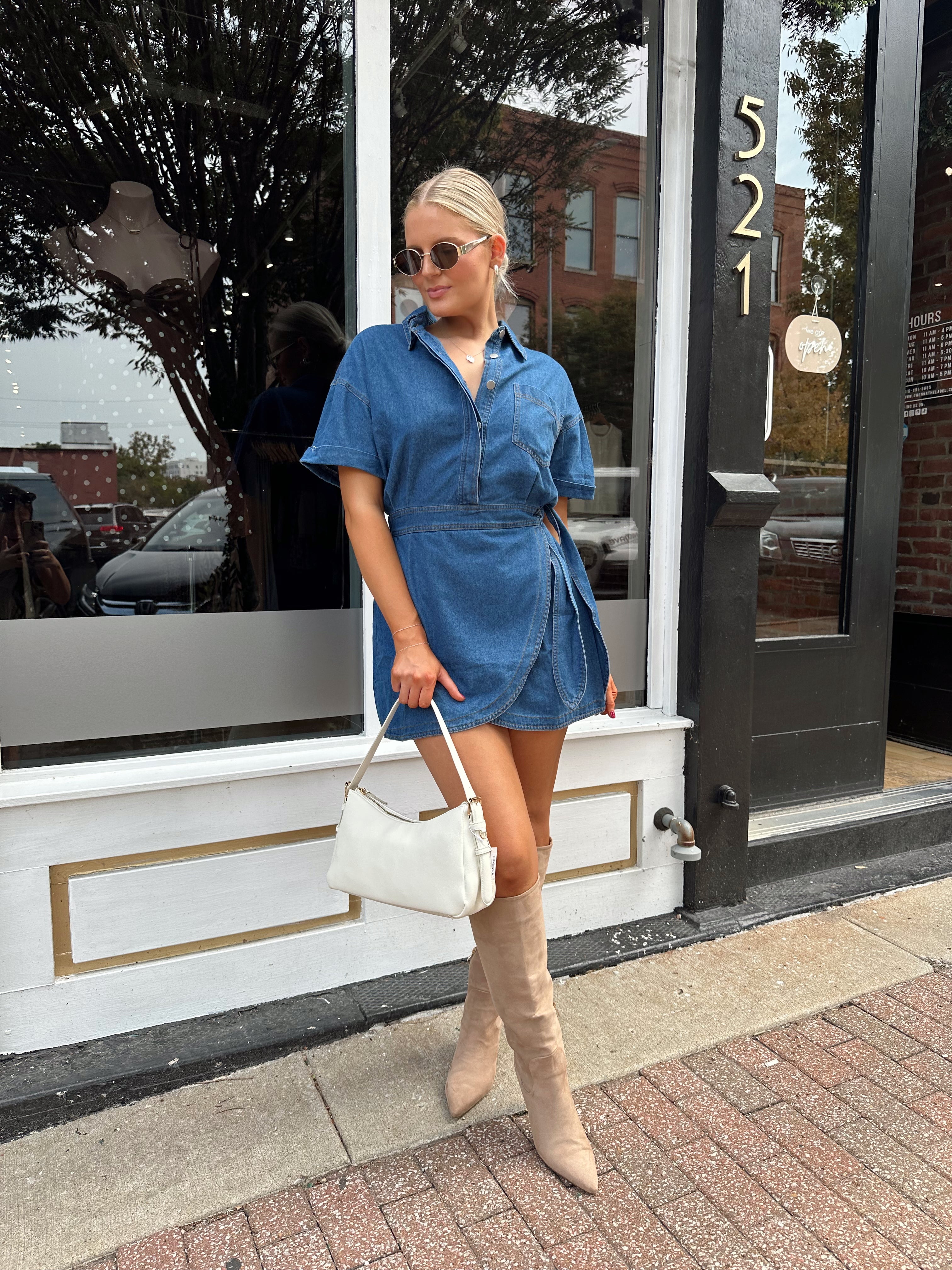 Woman wearing short sleeve dark wash denim dress with wrap skirt detail. 