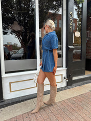 Woman wearing short sleeve dark wash denim dress with wrap skirt detail. 