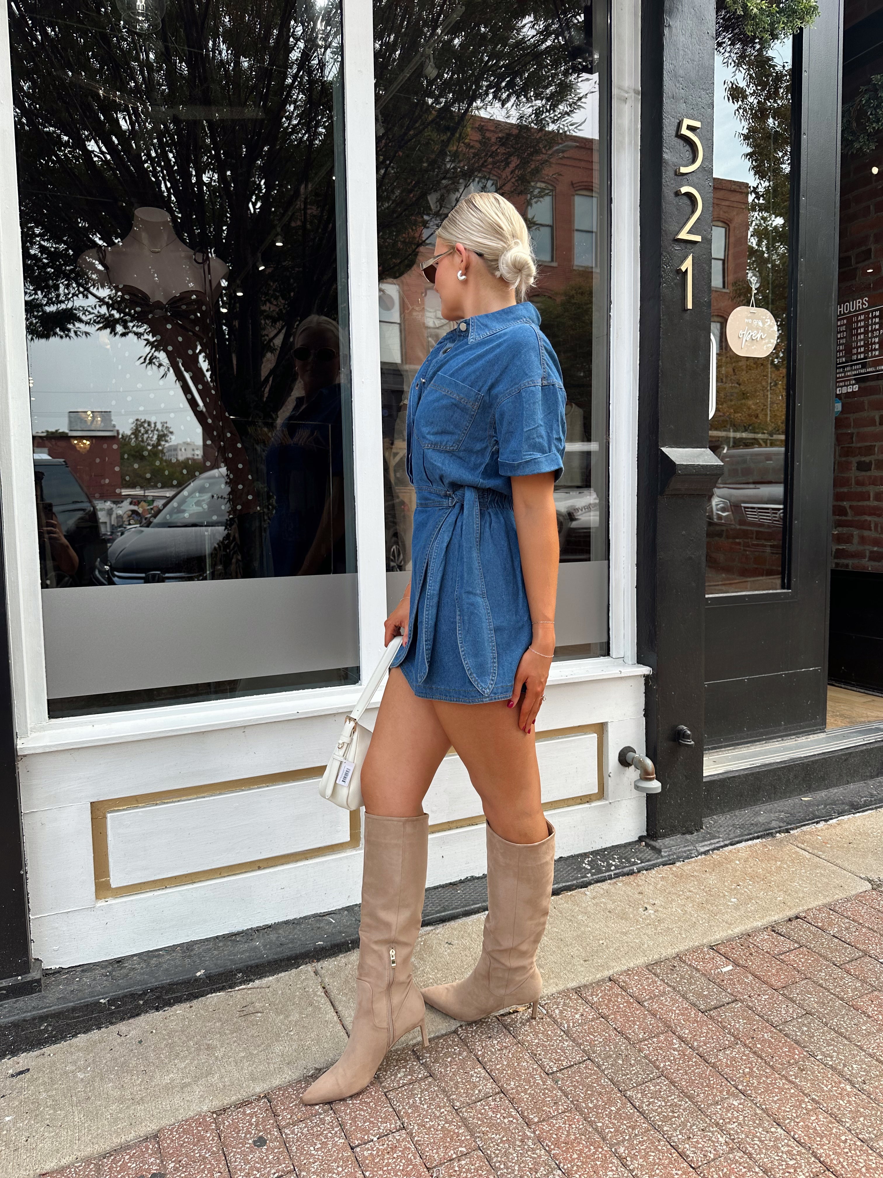 Woman wearing short sleeve dark wash denim dress with wrap skirt detail. 