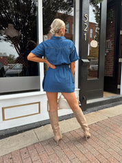 Woman wearing short sleeve dark wash denim dress with wrap skirt detail. 