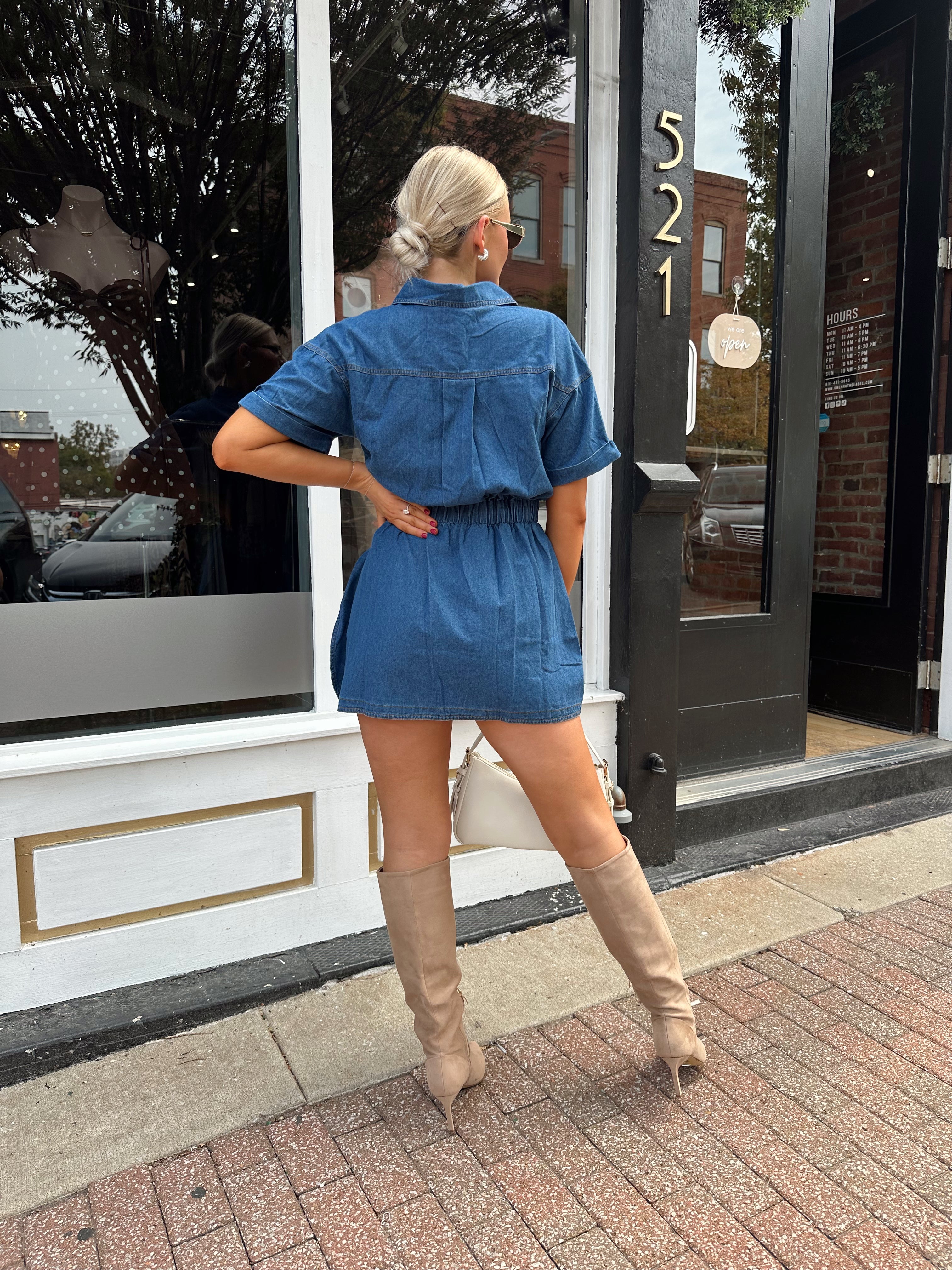 Woman wearing short sleeve dark wash denim dress with wrap skirt detail. 