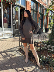 Woman wearing brown sweater two piece set with pleated mini skirt. 
