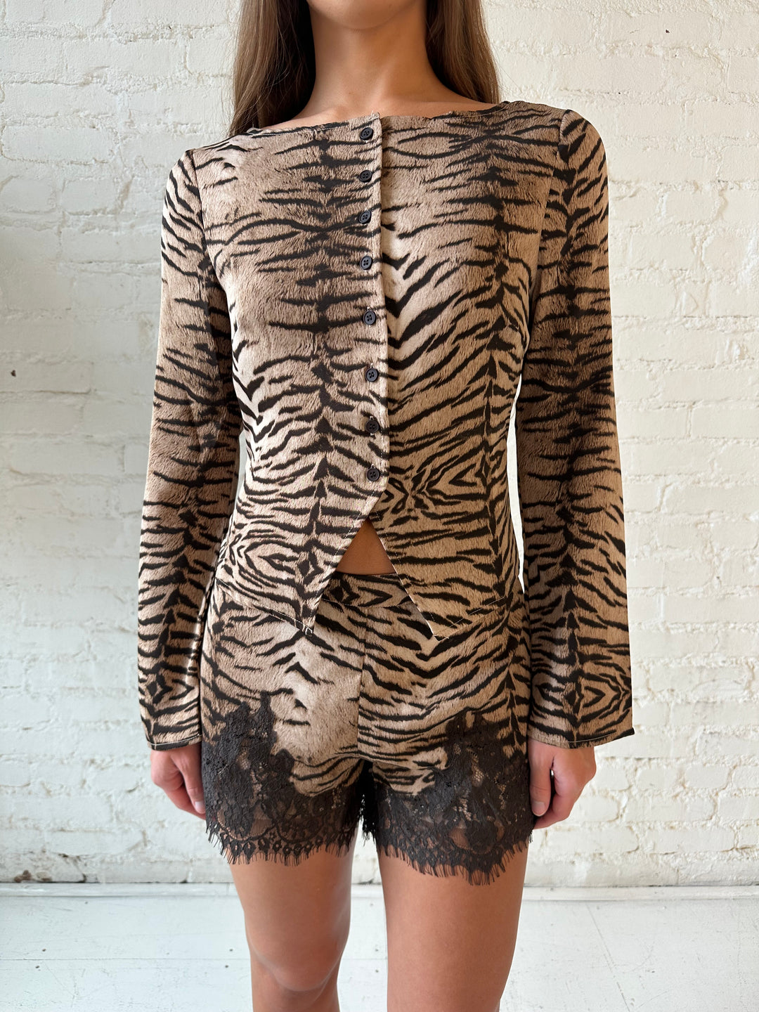 Woman wearing tiger print two piece set with high waisted shorts with lace trim detail, and sleeve button down top.
