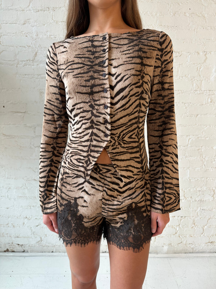 Woman wearing tiger print two piece set with high waisted shorts with lace trim detail, and sleeve button down top.
