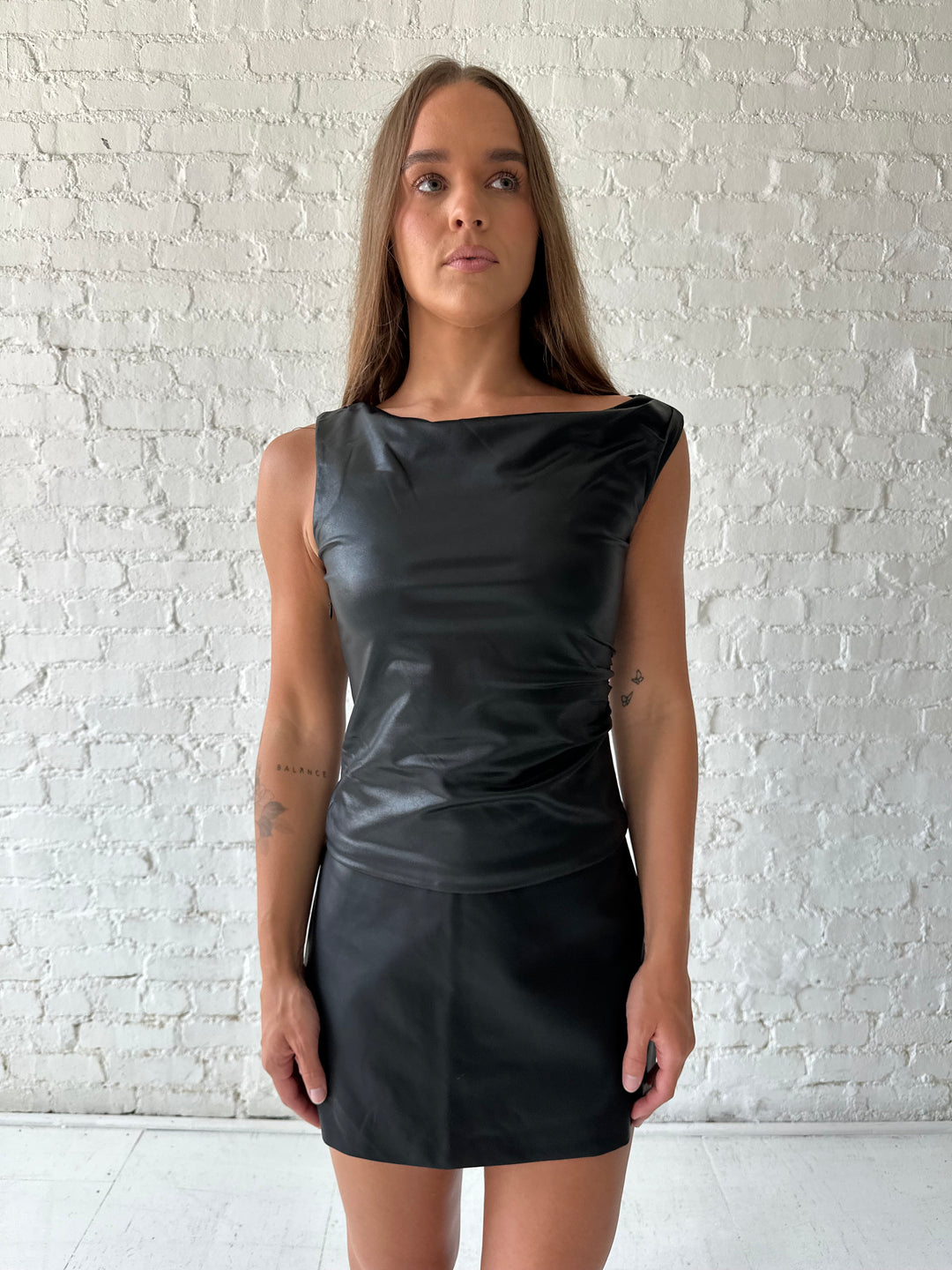 Woman wearing black leather top with a black leather mini skort.