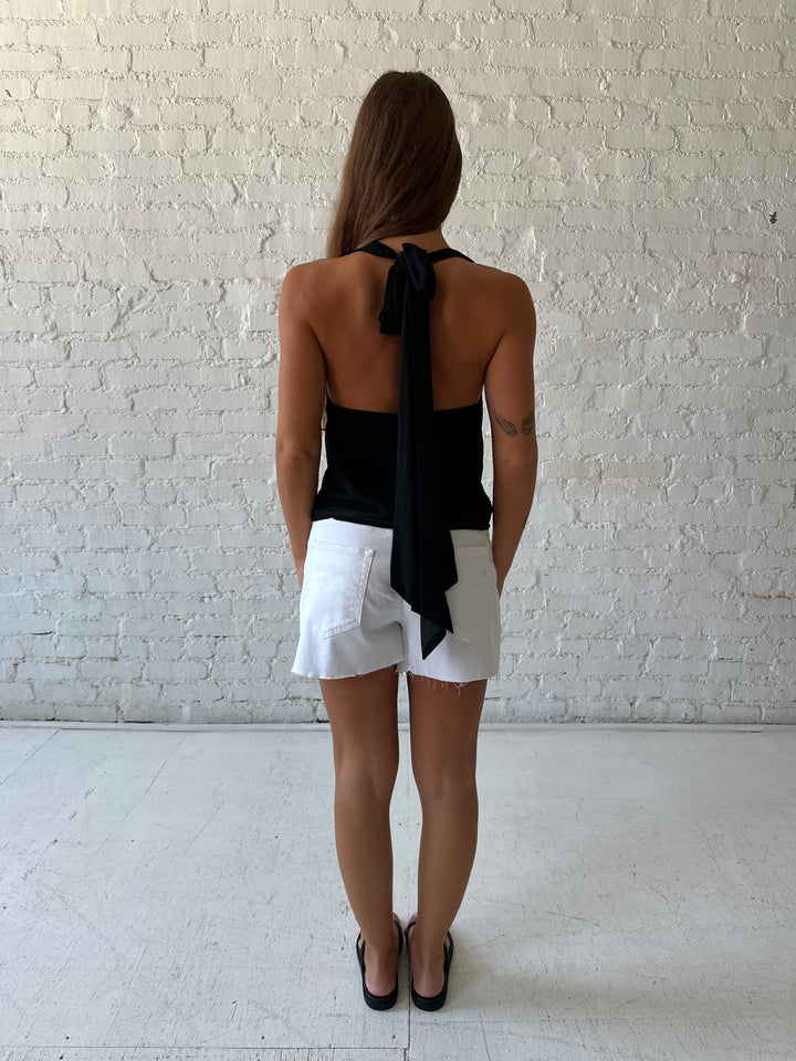 Woman wearing black halter cowl neck top with white denim shorts. 