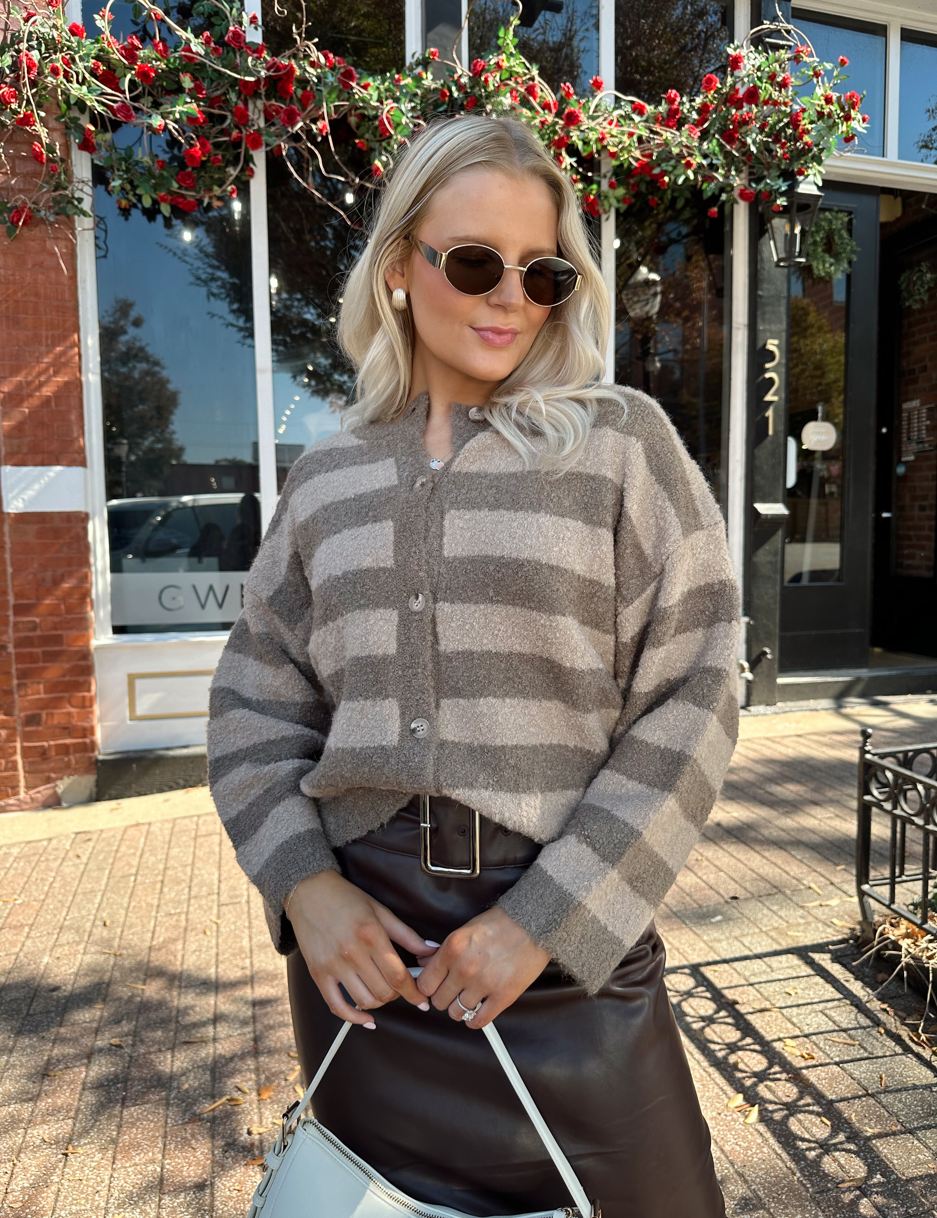 Woman wearing brown striped cardigan and dark brown leather skirt. 
