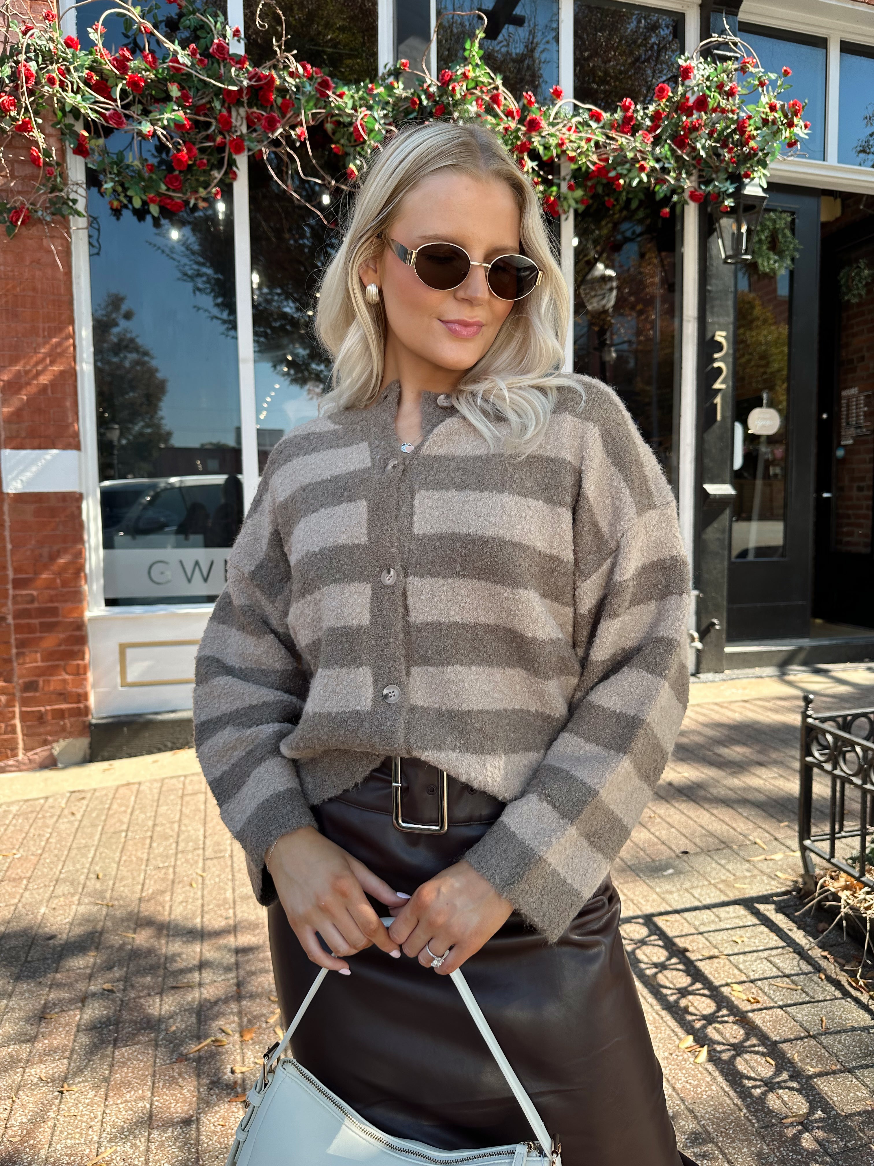 Woman wearing brown striped cardigan and dark brown leather skirt. 