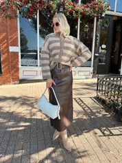 Woman wearing brown striped cardigan and dark brown leather skirt. 