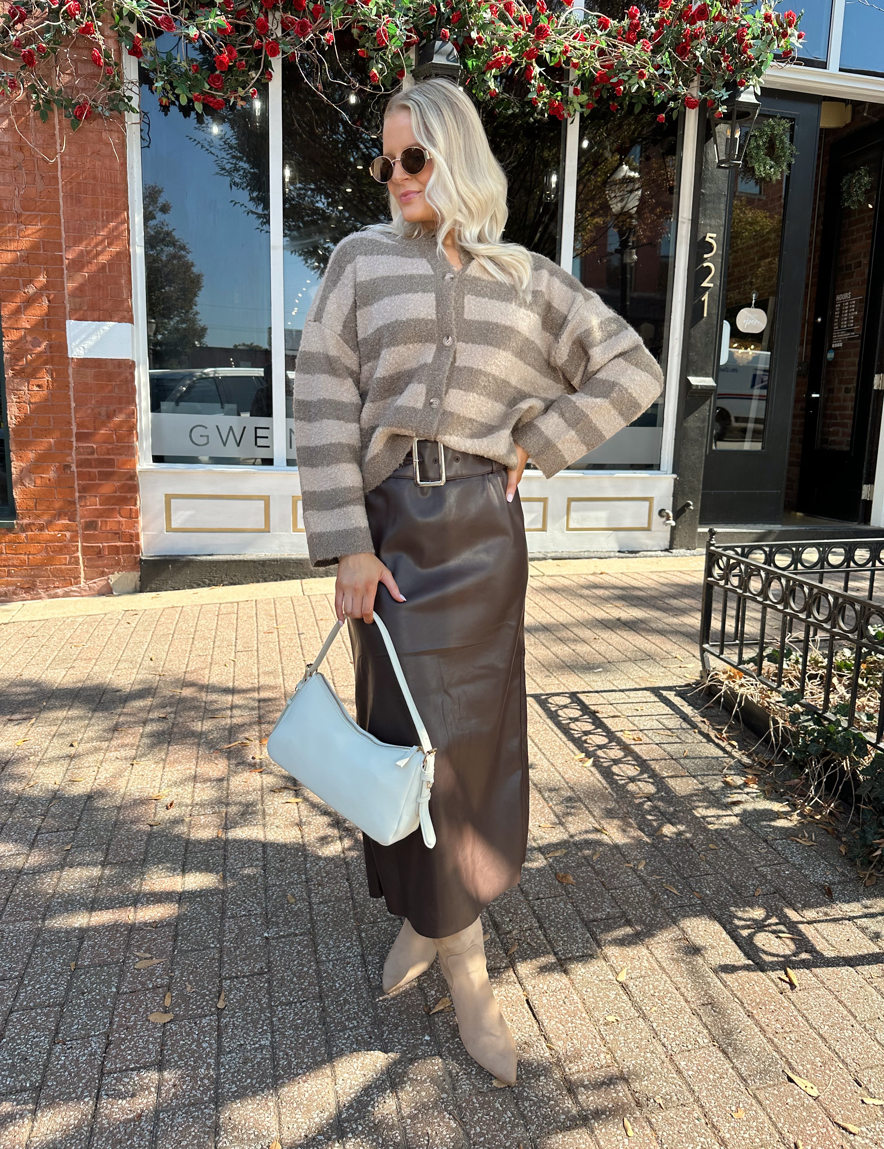 Woman wearing brown striped cardigan and dark brown leather skirt. 