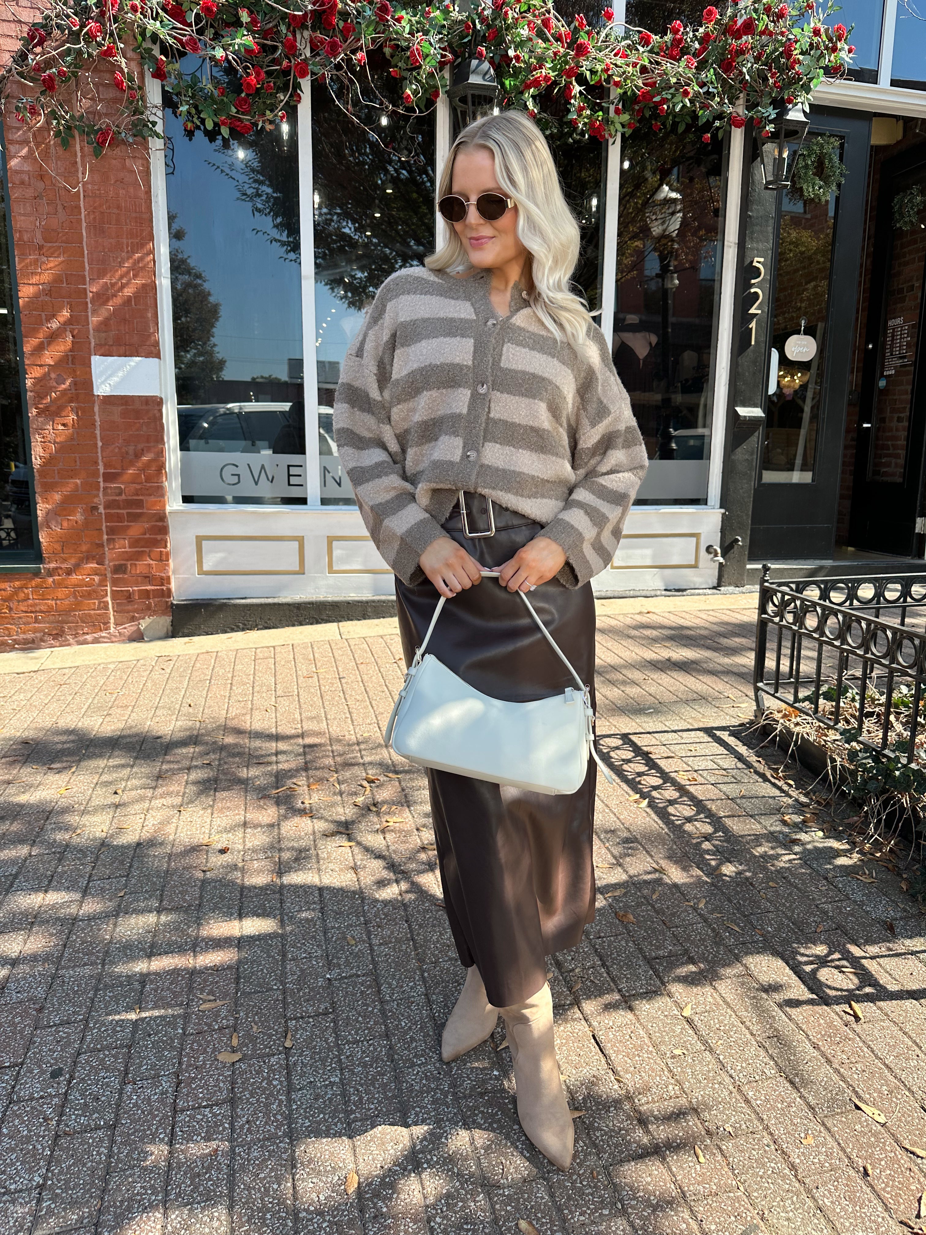 Woman wearing brown striped cardigan and dark brown leather skirt. 