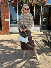 Woman wearing brown striped cardigan and dark brown leather skirt. 