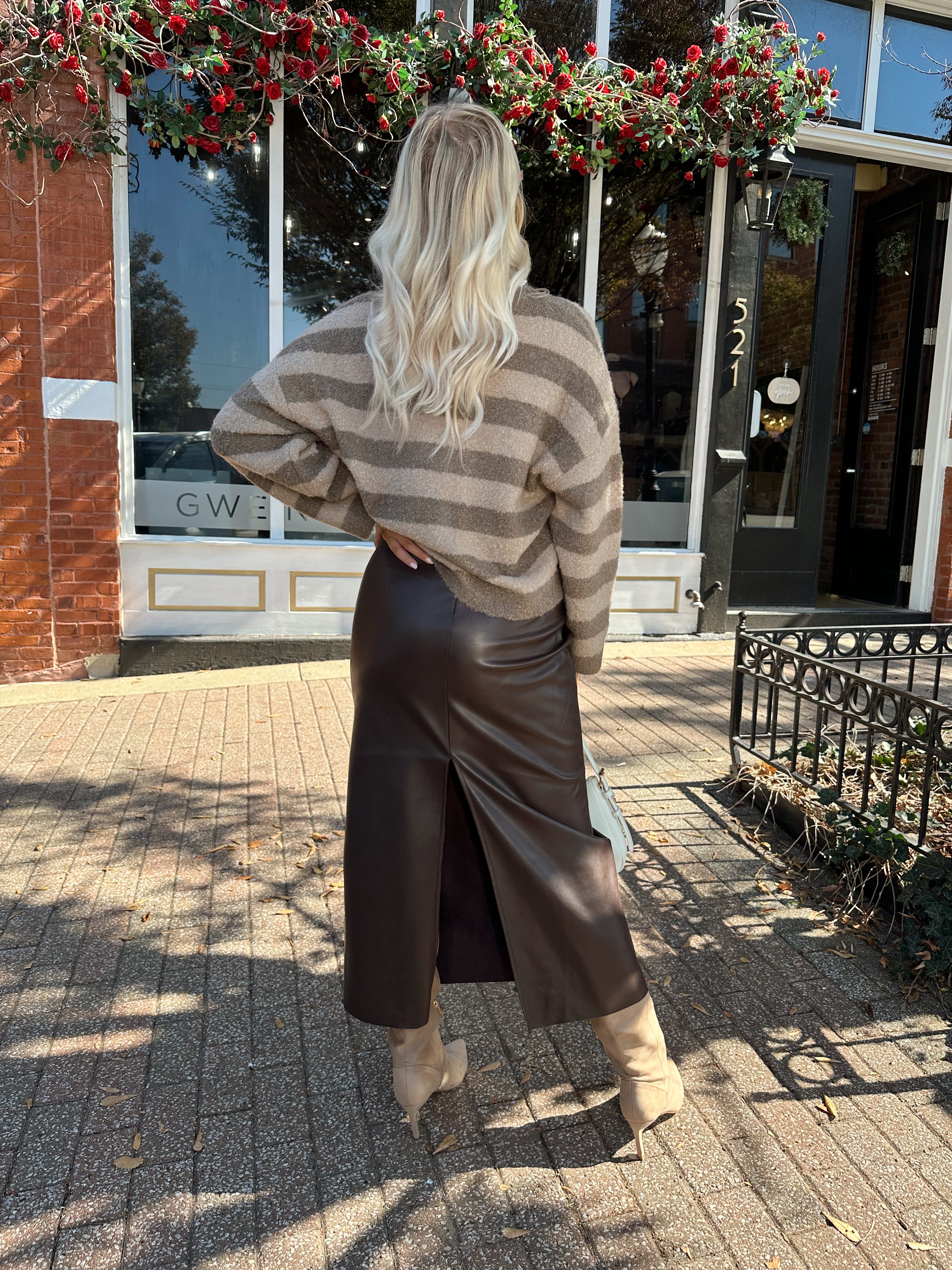 Woman wearing brown striped cardigan and dark brown leather skirt. 