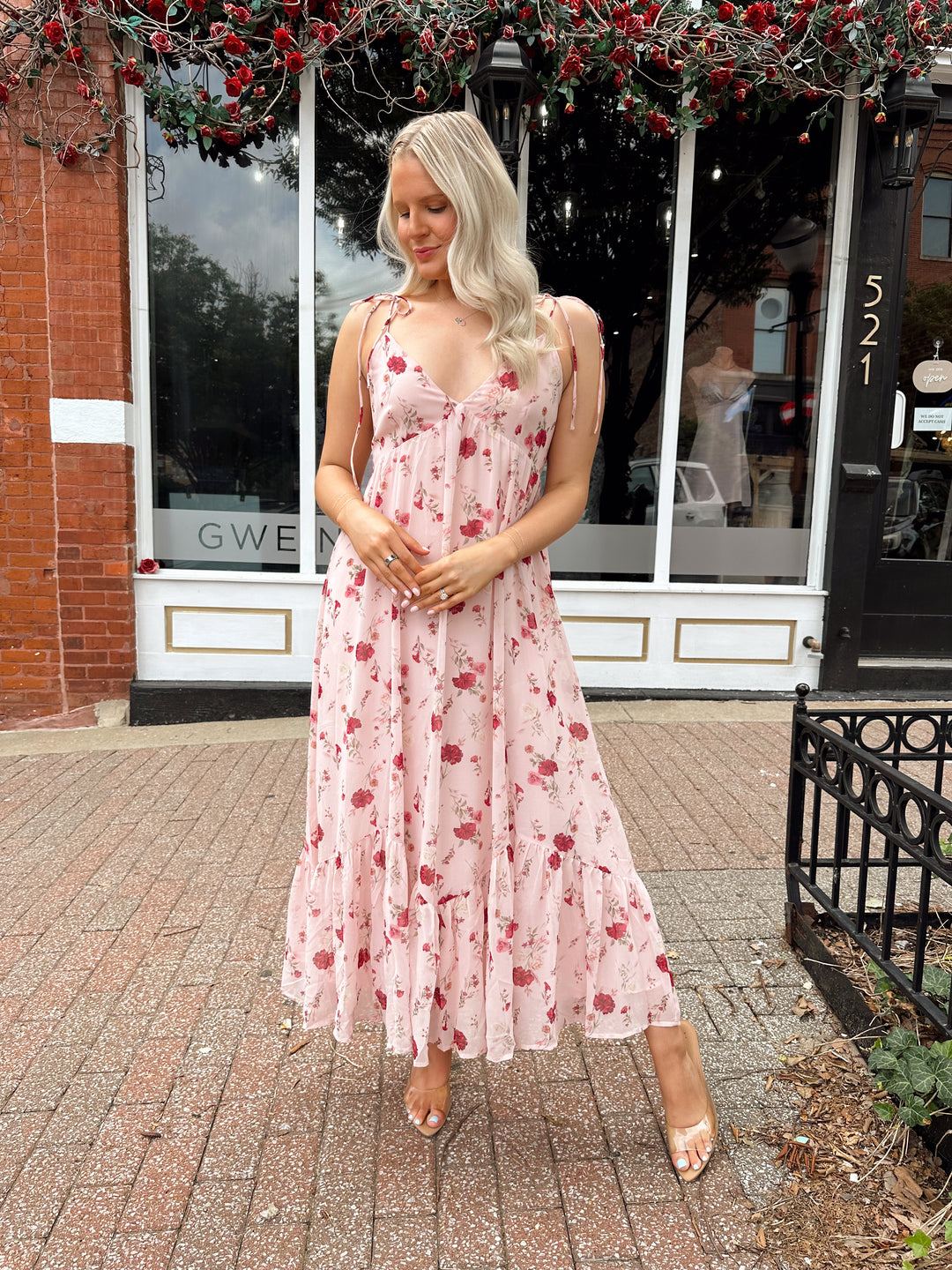 Woman wearing light pink maxi dress with floral pattern all over. 