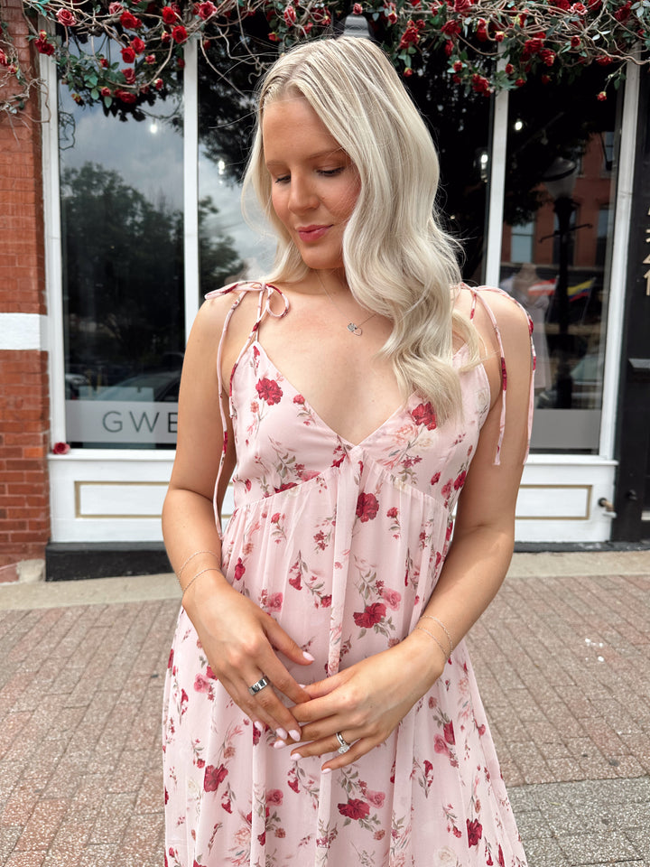 Woman wearing light pink maxi dress with floral pattern all over. 