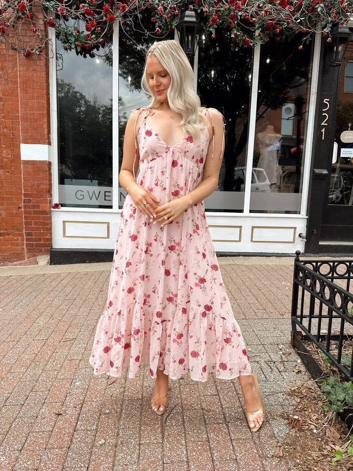 Woman wearing light pink maxi dress with floral pattern all over. 