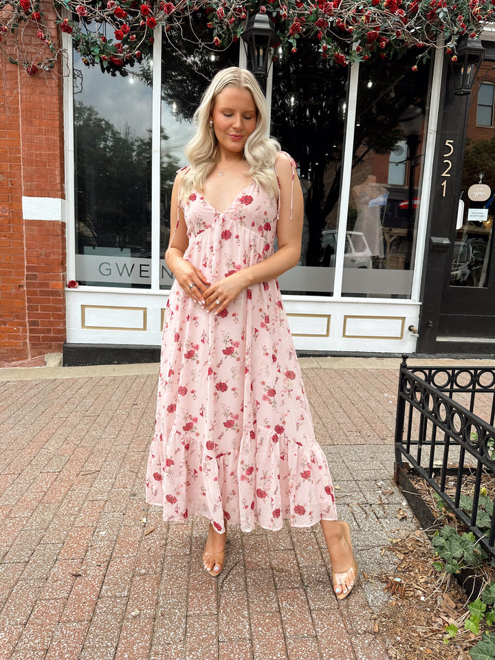 Woman wearing light pink maxi dress with floral pattern all over. 