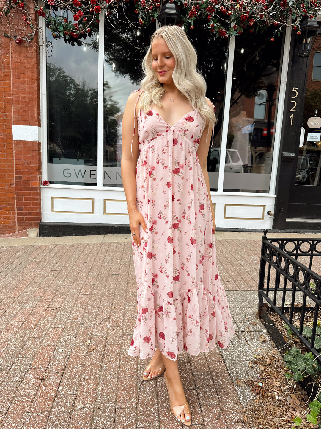 Woman wearing light pink maxi dress with floral pattern all over. 