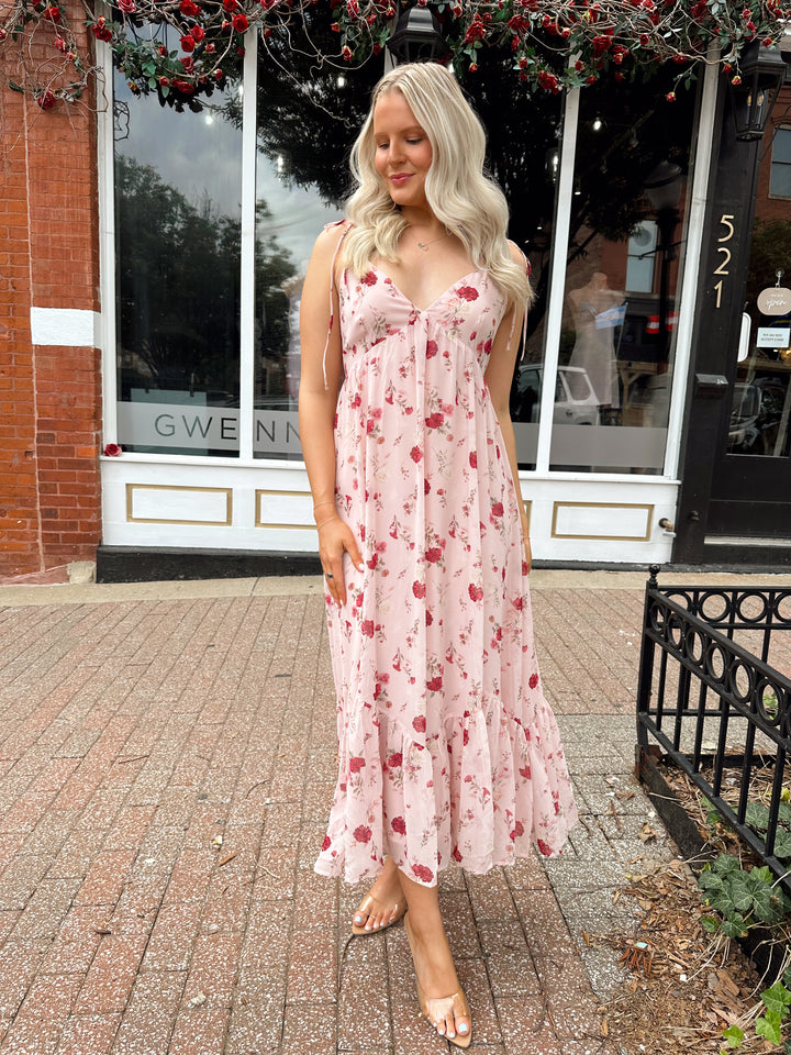 Woman wearing light pink maxi dress with floral pattern all over. 