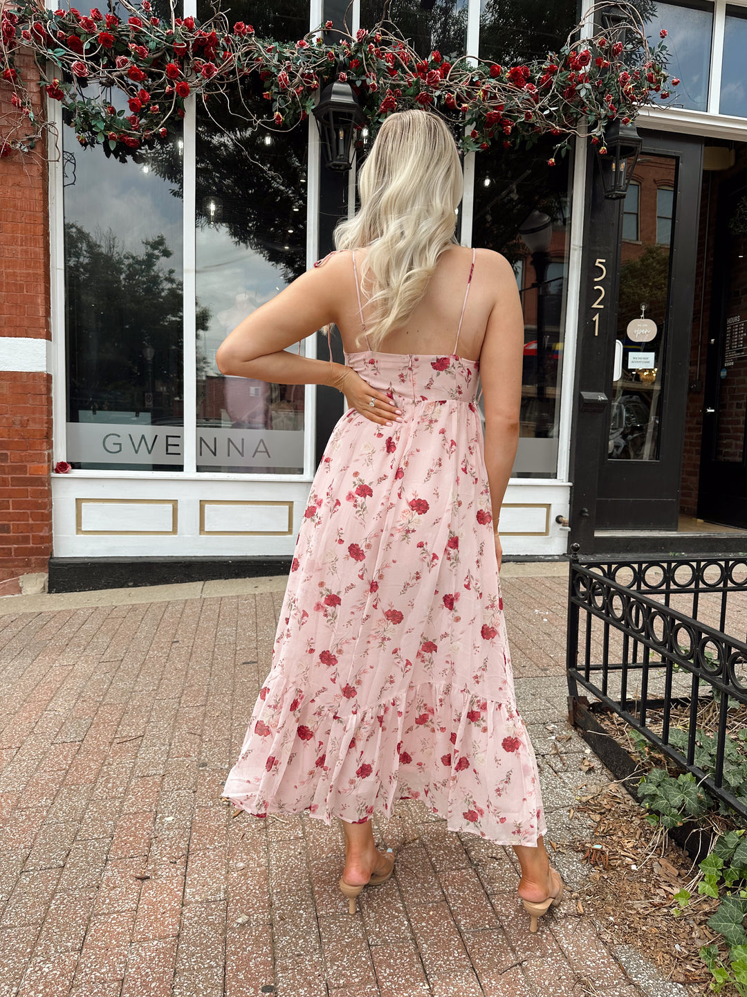 Woman wearing light pink maxi dress with floral pattern all over. 
