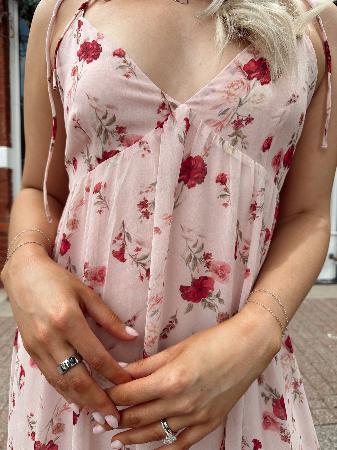 Woman wearing light pink maxi dress with floral pattern all over. 