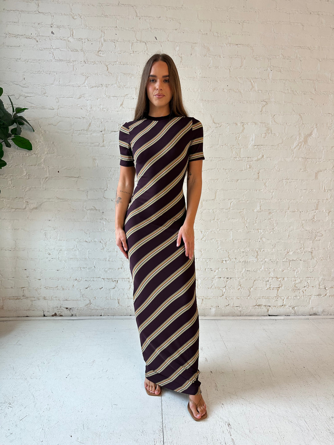 Woman wearing multi stripe maxi dress with short sleeves, and keyhole cutout on the back. 