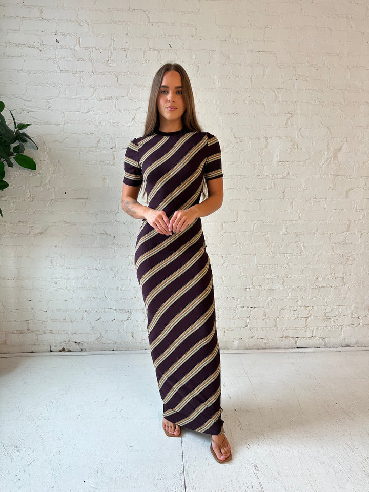 Woman wearing multi stripe maxi dress with short sleeves, and keyhole cutout on the back. 