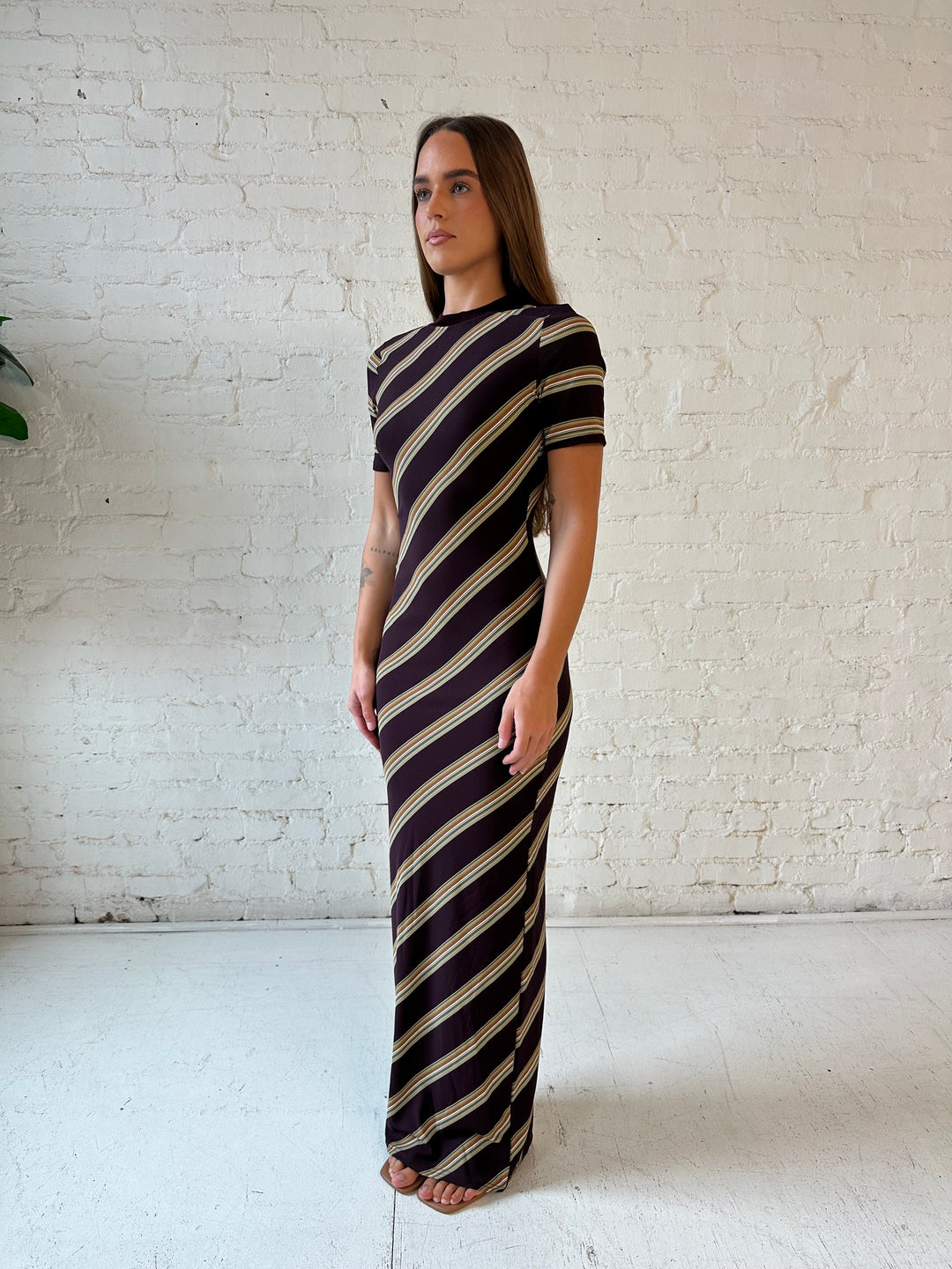 Woman wearing multi stripe maxi dress with short sleeves, and keyhole cutout on the back. 