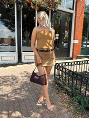 Woman wearing tan suede mini skirt with faux pockets and a brown suede belt.