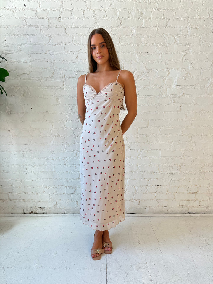 Woman wearing taupe midi dress with red floral with lace trim detailing. 