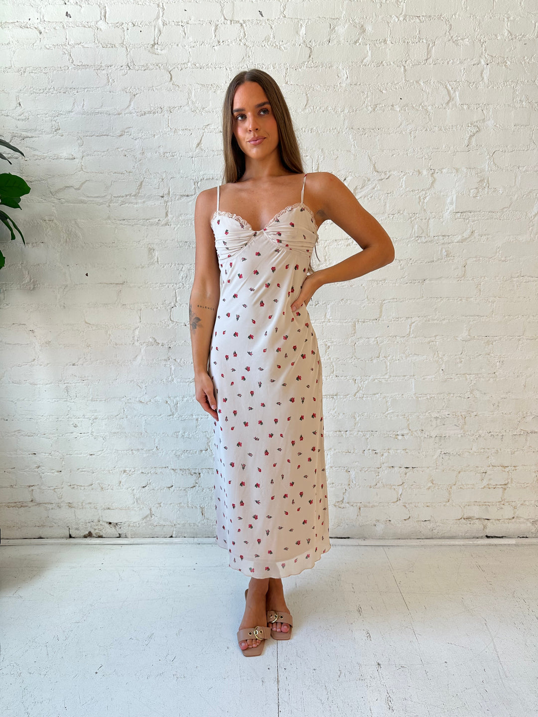 Woman wearing taupe midi dress with red floral with lace trim detailing. 