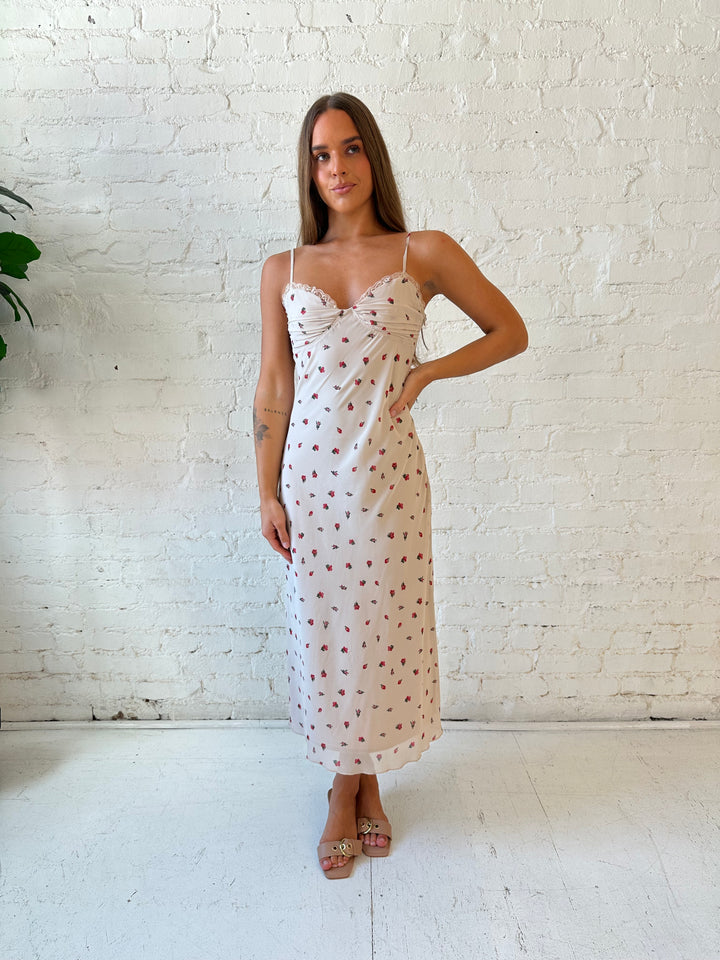 Woman wearing taupe midi dress with red floral with lace trim detailing. 