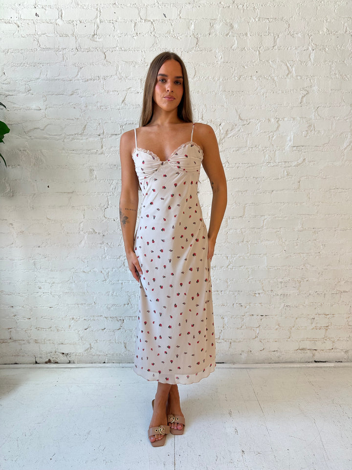 Woman wearing taupe midi dress with red floral with lace trim detailing. 