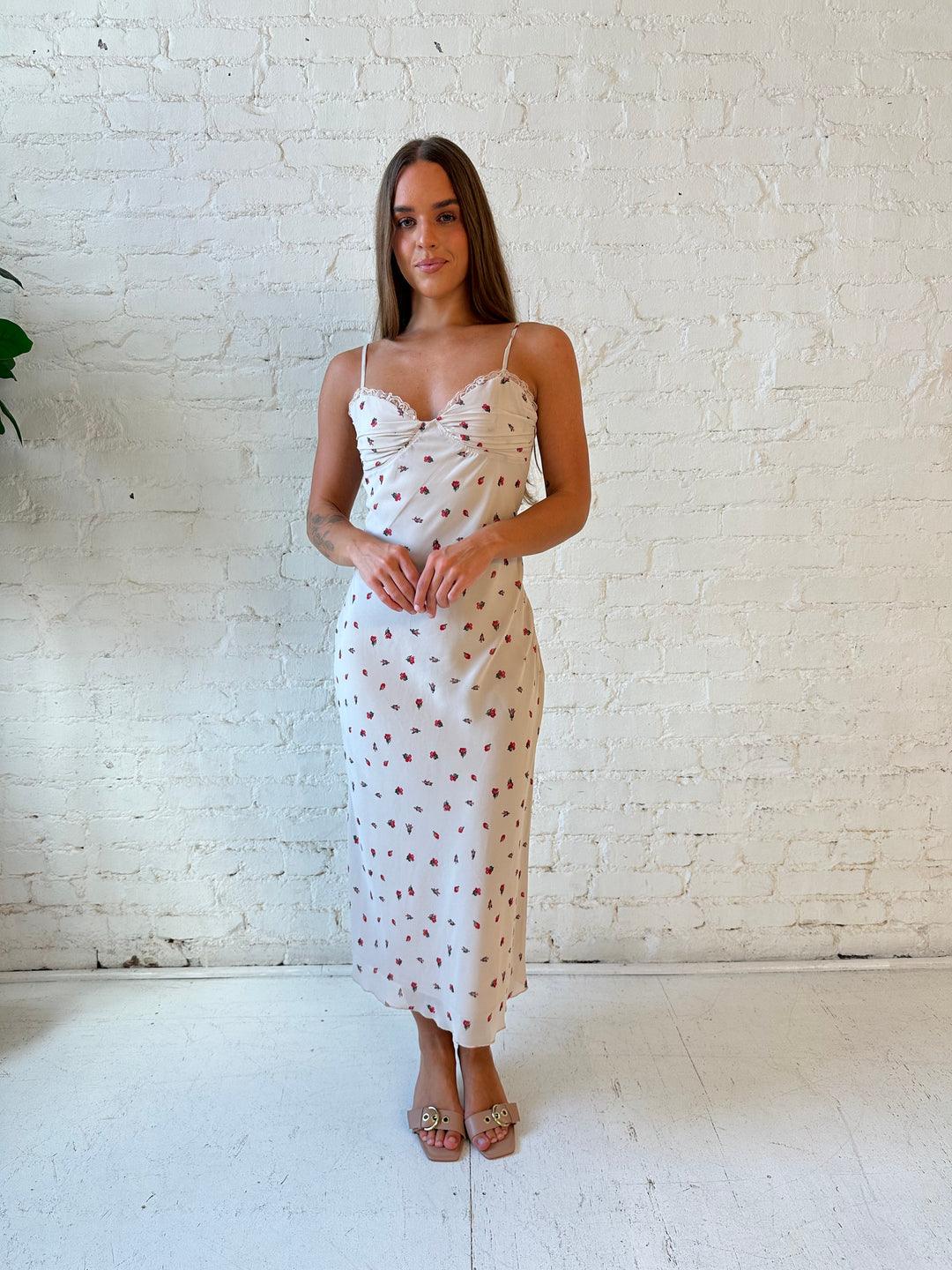 Woman wearing taupe midi dress with red floral with lace trim detailing. 